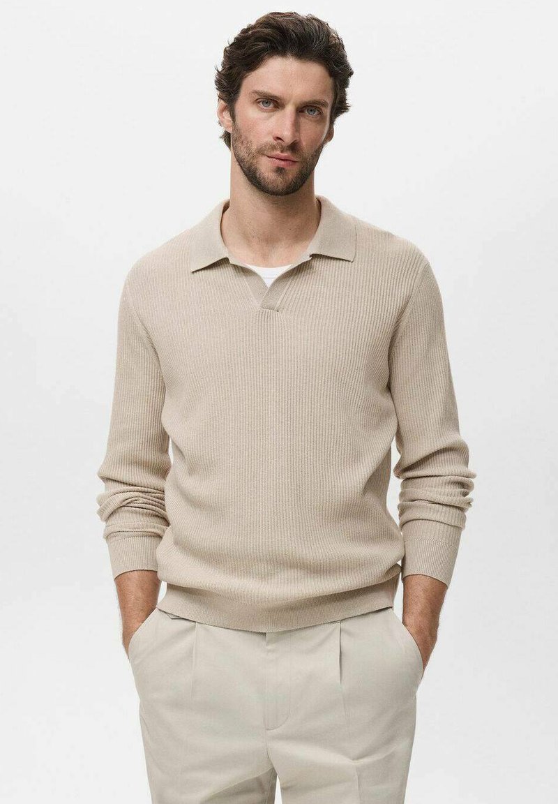 Suéter de punto acanalado beige con cuello y mangas largas, combinado con pantalones de color claro. Textura suave y un ajuste casual.