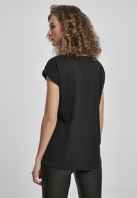 Schwarzes Kurzarm-T-Shirt mit umgeschlagenen Ärmeln, aus weichem Baumwollstoff gefertigt, mit lockerer Passform und einem schlichten Rückendesign.