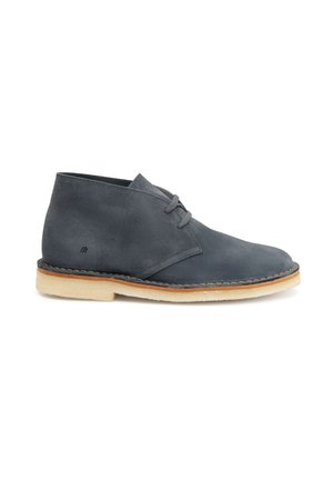 Scarpe chukka in suede grigio scuro con punta arrotondata, due lacci e suola in gomma beige a contrasto. Presentano un delicato dettaglio di cucitura.