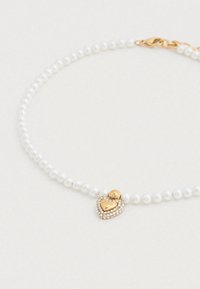 Λευκό περιδέραιο από μαργαριτάρια με χρυσό μενταγιόν καρδιά, διακοσμημένο με στρας. Διαθέτει κούμπωμα για ασφαλή φορεσιά.