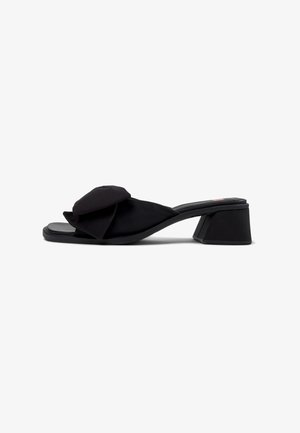 Sandale à glissière en satin noir avec un grand nœud à volants sur le dessus, bout ouvert et un talon en bloc géométrique robuste.