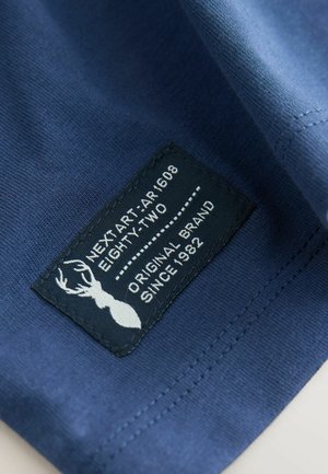 Marineblauer Stoff mit glatter Textur; das Etikett zeigt "NEXT ART AR1608 EIGHTY-TWO" und die Silhouette eines Hirsches.