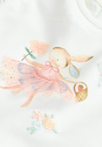 Tissu blanc avec une illustration imprimée d'un lapin en tutu rose, tenant une fleur, avec des fleurs brodées et un panier en dessous.