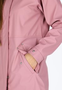 Giacca impermeabile rosa con finitura lucida, dotata di tasche laterali, chiusure a scatto e design snello per un aspetto moderno.