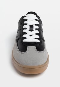 Baskets en cuir noir et suède gris avec lacets blancs, bout rond et semelle en gomme. Présentent une finition lisse et une texture contrastée.