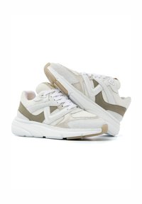 White mesh sneakers with beige accents, rounded toe, textured material, thick white midsole, and contrasting laces. Stylish design with layered elements.