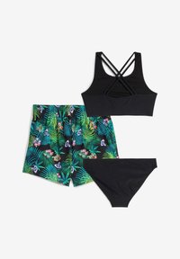 Top bikini nero con spatole incrociate, pantaloni da bagno con motivo floreale caratterizzati da foglie verdi e uno sfondo nero, e parte inferiore nera coordinata.