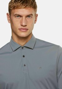 Grijze poloshirt met een kraag, twee knopen en een subtiele logo op de borst. Gemaakt van een gladde stof met een lichte glans.