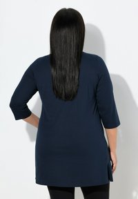 Granatowa tunika z rękawami do łokcia, wykonana z gładkiego materiału, z bocznym rozcięciem i luźnym krojem, widziana od tyłu.