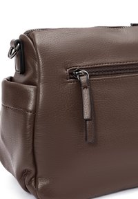 Bolso de cuero marrón texturizado con un bolsillo con cremallera y un anillo lateral. Diseño compacto con bordes suaves y hardware mínimo.