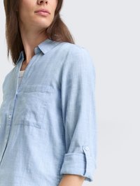 Lyseblå, rutete skjorte med knapper og krage, en brystlomme og oppbrettede ermer. Myk tekstur og uformelt design.