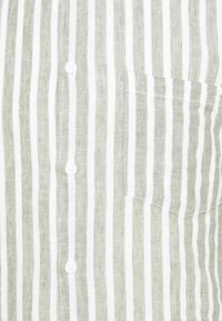 Camicia con bottoni realizzata in tessuto leggero, caratterizzata da strisce sottili alternate di verde e bianco, con taschino e bottoni bianchi.