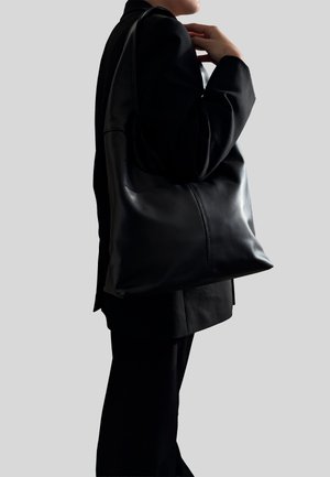 Czarna skórzana torba na ramię o miękkiej fakturze, minimalistycznym designie i solidnych rączkach; posiada przeszycie dla dodatkowej struktury.