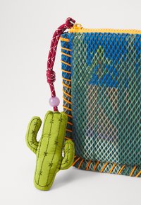 Bunte Netztasche mit einem blauen und grünen Farbverlauf, orange und rosa Nähten sowie einem grünen, kaktusförmigen Reißverschluss-Anhänger mit gestickten Details.