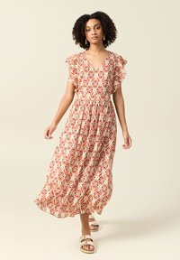 Maxiklänning med V-ringning, korta volangärmar och ett geometriskt mönster i orange och krämfärg. Tillverkad av lätt tyg har den en elastisk midja.