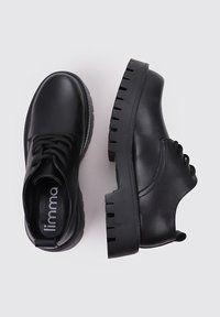 Zapatos de cuero negros con un diseño de cordones, punta redondeada y suela resistente y estriada. Textura suave con mínimo detalle y poco branding visible.