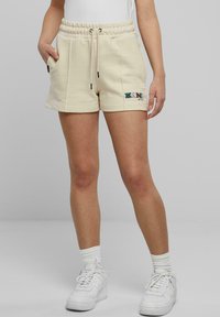 Beige sweatshorts med elastisk midjeband, dragsko, sidofickor och logotypdetalj. Tillverkade av mjukt tyg och har en avslappnad passform.