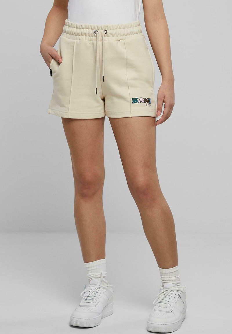 Beige sweatshorts med elastisk midjeband, dragsko, sidofickor och logotypdetalj. Tillverkade av mjukt tyg och har en avslappnad passform.