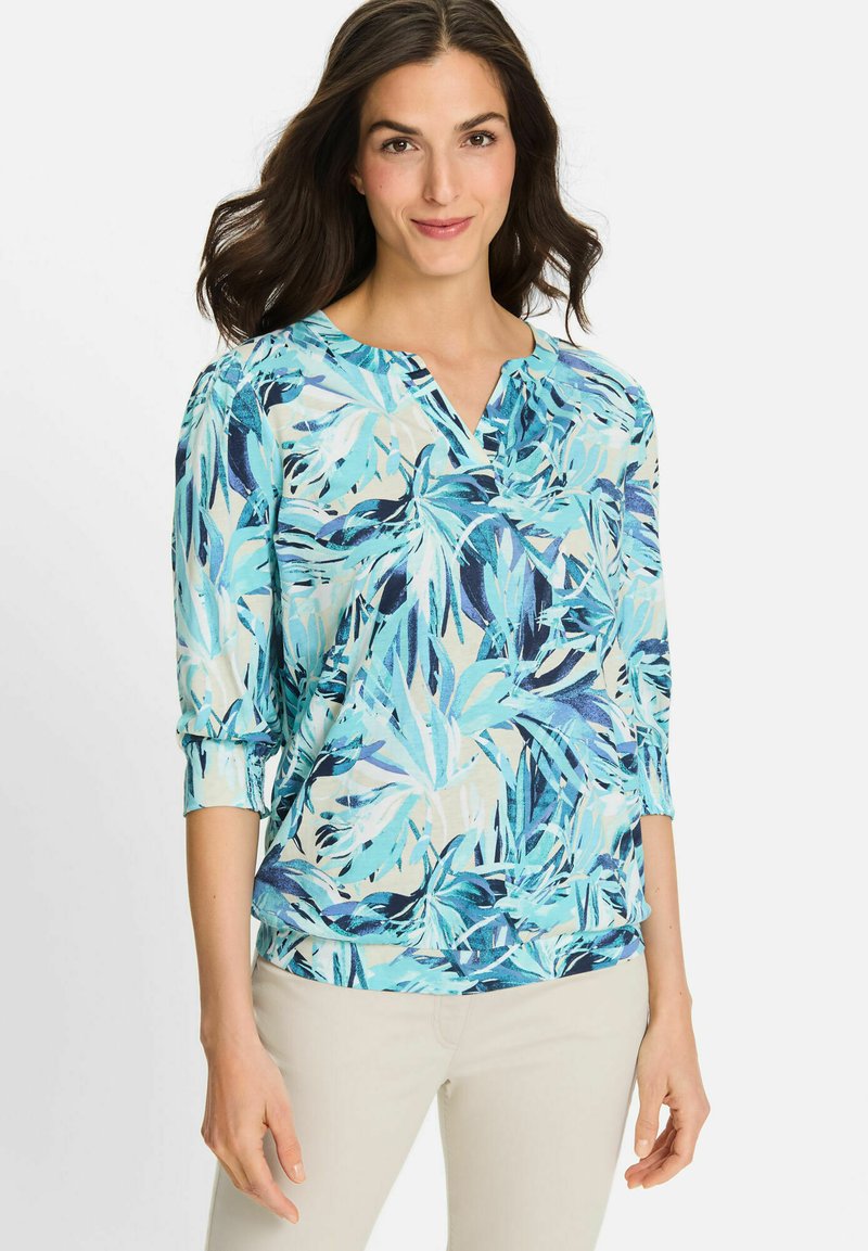 Bloemdruk blouse in teal en blauw, met een ronde halslijn, driekwartmouwen en een relaxte pasvorm. Gladde stof met bladvormen.
