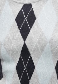 Pull en tricot gris avec un motif en losanges argyle noir et bleu clair, agrémenté de coutures blanches contrastantes. Texture douce.