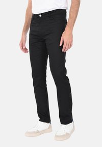 Pantaloni neri slim-fit in cotone con tasche frontali, zip e un delicato dettaglio di cucitura vicino all'orlo. Progettati per un look moderno.