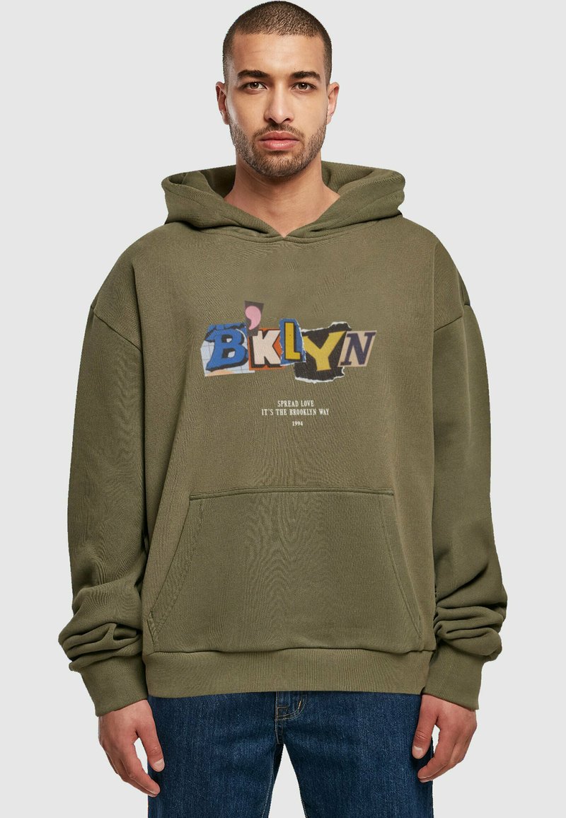 Olívazöld kapucnis felső, elülső zsebbel, amelynek grafikus szövege színesen van feltüntetve, és azt mondja: "BKLYN", alatta pedig egy kisebb szöveg található.