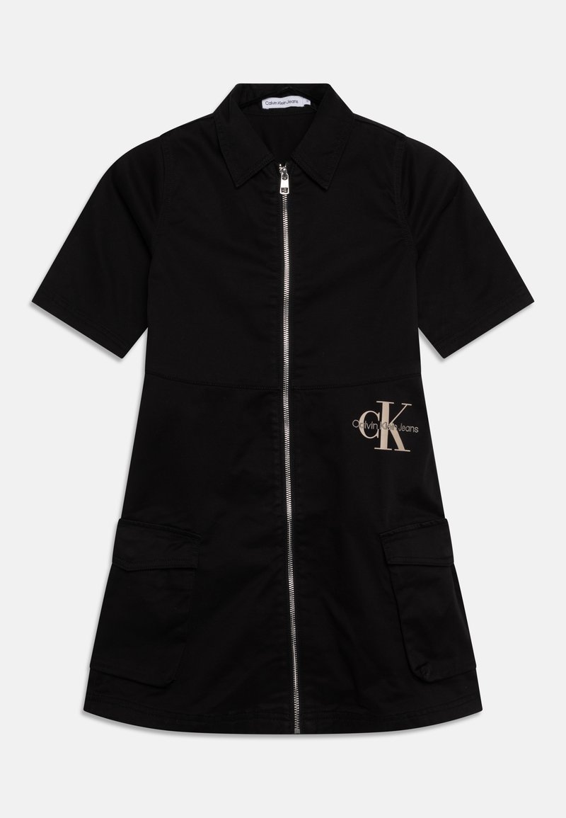 Robe noire à manches courtes avec fermeture éclair frontale, col, deux grandes poches et logo Calvin Klein Jeans beige sur le côté droit.
