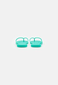 Turkosa flip-flops med mjukt gummimaterial, platta sulor och tunna remmar. Texturerad fotbädd för grepp, designade för avslappnad användning.