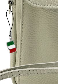 Lichtbeige textuur tas met een zilveren bevestiging waarop een klein, wapperend Italiaans vlaggetje charm in groen, wit en rood is bevestigd.