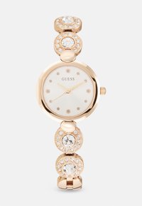 Rose gold watch with a round face, white dial, and crystal hour markers. Features a bracelet-style band adorned with circular crystal accents.