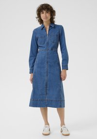 Rochie din denim cu mâneci lungi, guler, două buzunare pe piept și închidere cu nasturi pe față. Rochia are talie ajustată și o fustă evazată.