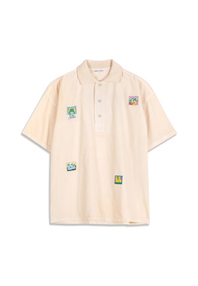 Polo beige clair à manches courtes avec quatre écussons carrés colorés présentant des motifs abstraits et de dessins animés sur le devant.