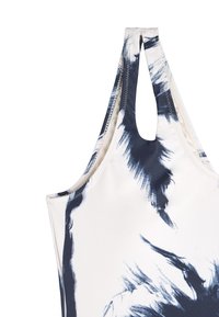 Strój kąpielowy o białej bazie z abstrakcyjnymi wzorami w granatowe pociągnięcia pędzla. Posiada cienkie ramiączka i wycięty tył.