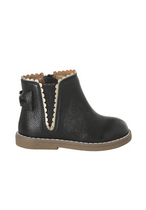 Black toddler ankle boot with beige scalloped trim, side elastic panel, decorative bow at heel, and brown textured sole.