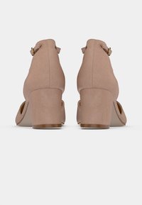 Beiginiai aukštakulniai batai su minkštu audinio viršumi, apvaliu pirštu, plačiu blokuotu kulnu ir reguliuojama juostele su auksine sagtimi.