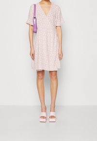 Pink floral dress with short flutter sleeves, V-neck, and a relaxed fit. Paired with pink platform sandals and a lavender bag.