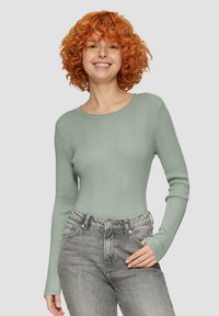 Jasnozielona, prążkowana koszula z długim rękawem i okrągłym dekoltem, zestawiona z jasnoszarymi spodniami z wysokim stanem. Prosty i przylegający fason.