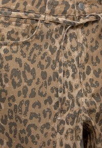 Pantalon imprimé léopard en tons beige et marron, avec un tissu texturé, des poches avant et une taille à cordon.