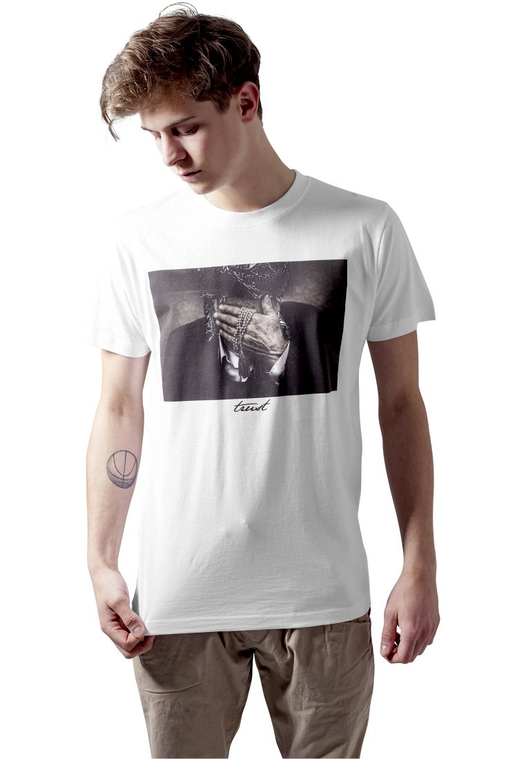 White cotton t-shirt featuring a black and white print of a person's hand covering their face, with the word "trust" below the image.