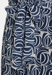 Námornícky a krémové šaty s geometrickým vzorom, látka je jemná s úzkym pásom a veľkým detailom mašle.