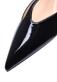 Scarpa con punta affusolata in vernice nera, con una scollatura bassa e dettagli di cucitura lungo i bordi, caratterizzata da una finitura liscia e lucida.