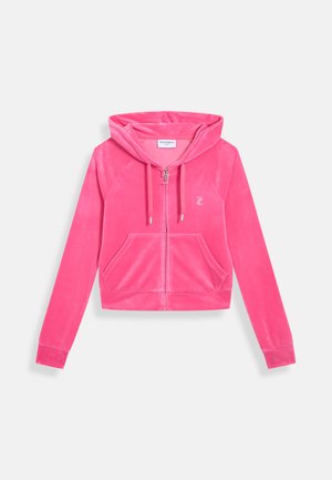 Roze ritsjack in zachte fluweel. Beschikt over een capuchon, twee vo zakken en een klein geborduurd logo. Kort model met lange mouwen.