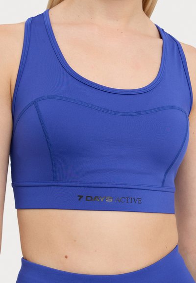 Blue athletic bra with a scoop neckline, seamless design, and embossed logo detailing at the hem. Made from stretchy, moisture-wicking material.