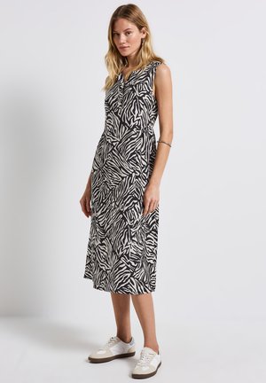 Black and white zebra print sleeveless dress with a relaxed silhouette, knee-length, paired with white and light gray sneakers.
