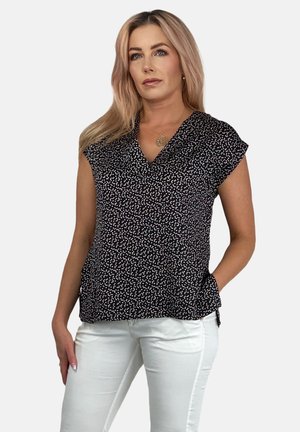 Black sleeveless blouse with a V-neck, featuring a white speckled pattern and a relaxed fit. Paired with white slim-fit pants.