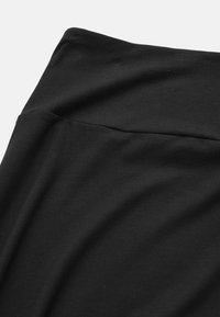 Zwarte elastische stof met een gladde textuur, voorzien van een brede tailleband en een subtiele geplooide detail. Geschikt voor sportkleding of casual gebruik.