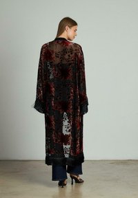 Kimono transparent negru cu modele florale burgundie, accente cu franjuri la mâneci și tiv, cu față deschisă și un design fluid.