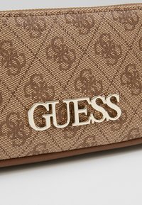 Hnědá texturovaná peněženka se vzorem diamantů a zlatým logem, doplněná hladkým lemováním.