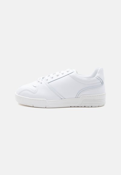 Λευκό sneaker χαμηλής κοπής με σχέδιο κορδονιών, λείο συνθετικό επάνω μέρος και μοτίβο από καουτσούκ στη σόλα, σε απλό φωτεινό φόντο.