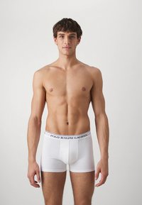 Vita bomullsboxershorts med ett elastiskt midjeband som har "POLO RALPH LAUREN" i mörkblått. Figursydd design, slät textur.